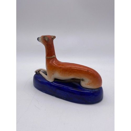 252 - STAFFORDSHIRE RECUMBENT WHIPPET INKWELL A/F AND PAIR OF SEATED SPANIELS