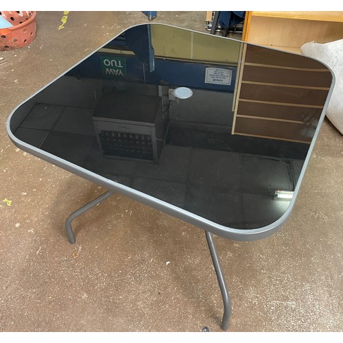 190 - GREY TUBULAR METAL PATIO TABLE AND FOUR STACKING CHAIRS WITH STRIPED CUSHIONS AND PARASOL