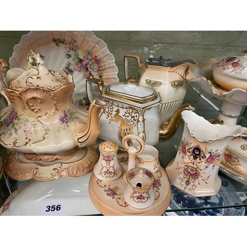 356 - CROWN DEVON BLUSH IVORY FLORAL TEAPOTS ON STANDS, CRUET SETS AND COMPORT, LIDDED JUG, SOME A/F JUG &... 