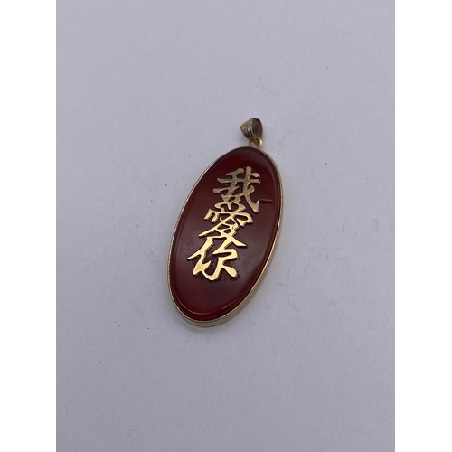 720 - UNMARKED YELLOW METAL OVAL MOUNTED AGATE PENDANT WITH CHINESE SCRIPT 8G APPROX OVERALL