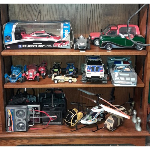 253 - TWO SHELVES OF REMOTE CONTROL MODEL RACE CARS AND REMOTE CONTROL SYSTEM CONTROLLERS, HELICOPTERS AND... 