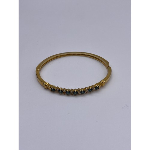 714 - UNMARKED YELLOW METAL CZ AND BLUE STONE BANGLE