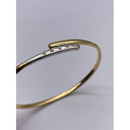 712 - 18K YELLOW AND WHITE GOLD CROSS OVER BANGLE 6G APPROX