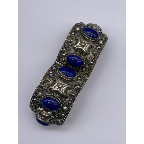 693 - ETHNIC WHITE METAL AND BLUE CABOCHON CUFF BANGLE AND A SILVER CROSS ON TRACE CHAIN