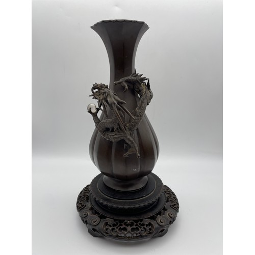 441 - JAPANESE BRONZE LOBED VASE DECORATED WITH DRAGON AND ORB ON HARDWOOD STAND