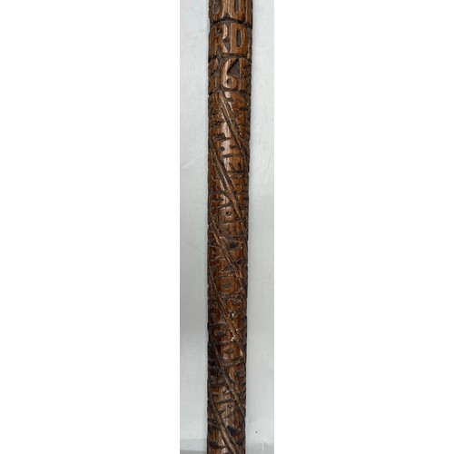 216 - INTERESTING CARVED WOODEN WALKING STICK DATED WITH NAME AND RELIGOUS TEXT (SANS HANDLE)