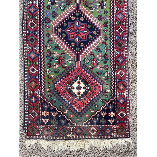 232 - 20TH CENTURY CAUCASIAN CARPET RUNNER WITH LOZENGE MEDALLIONS ON A GREEN GROUND 68CM X 288CM APPROX