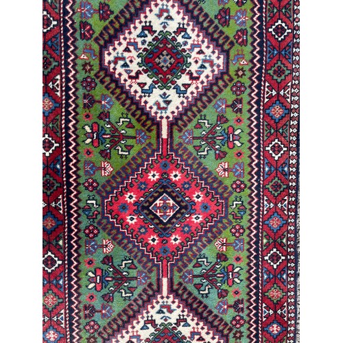 232 - 20TH CENTURY CAUCASIAN CARPET RUNNER WITH LOZENGE MEDALLIONS ON A GREEN GROUND 68CM X 288CM APPROX