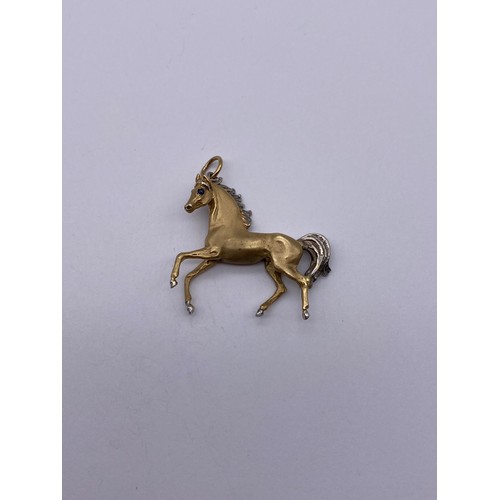 447 - 9CT CAST GOLD HORSE CHARM WITH INSET BLUE STONE EYES 12.8G APPROX