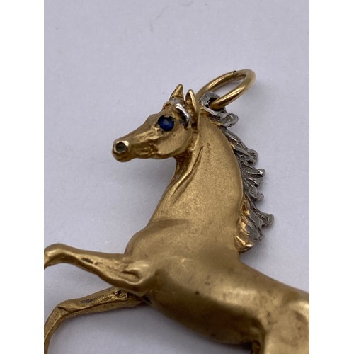 447 - 9CT CAST GOLD HORSE CHARM WITH INSET BLUE STONE EYES 12.8G APPROX