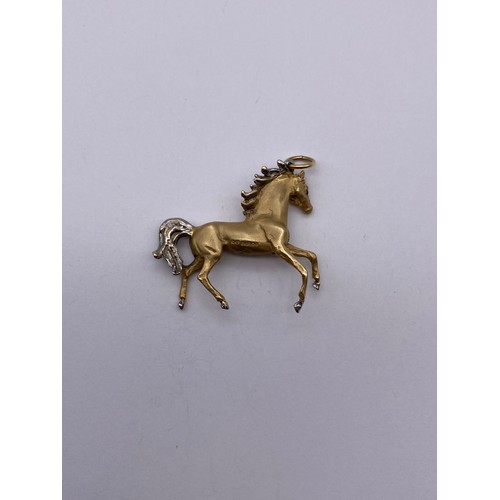 447 - 9CT CAST GOLD HORSE CHARM WITH INSET BLUE STONE EYES 12.8G APPROX