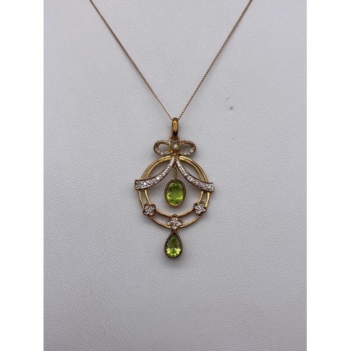 425 - EDWARDIAN CIRCULAR DISC PERIDOT AND DIAMOND BOW PENDANT ON FINE TRACE CHAIN 4.1G APPROX