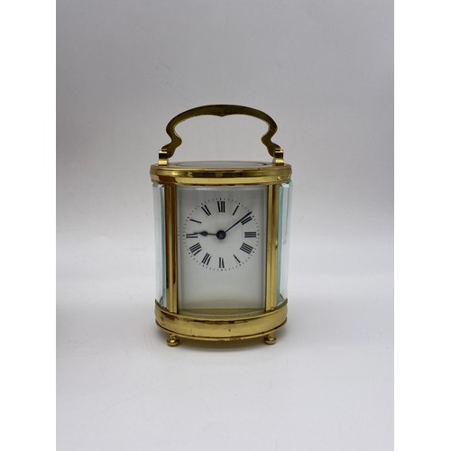 374 - LEATHER CASED TRAVELLING GILT BRASS OVAL CARRIAGE CLOCK