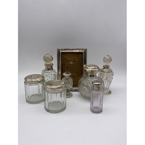 553 - SILVER RECTANGULAR EASEL BACK PHOTO FRAME AND VARIOUS SILVER AND PLATED TOPPED DRESSING TABLE BOTTLE... 