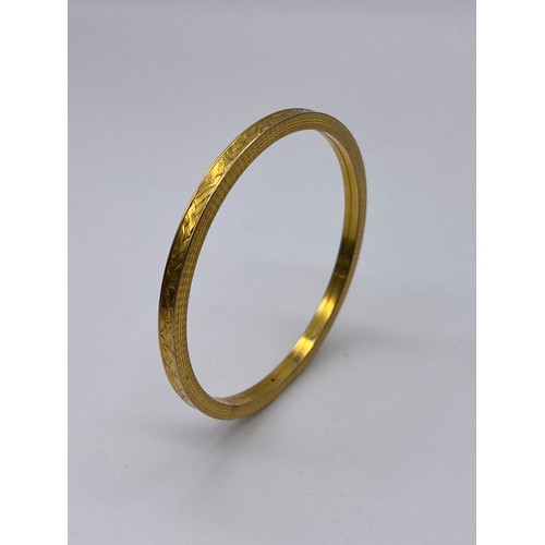 690 - THREE PLATED AND GOLD TONE COLOURED BANGLES (INC. BADEN EXAMPLE) AND AN ORNATE BONE BANGLE WITH RED ... 