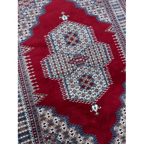 63 - MULTI PATTERN GEOMETRIC CARPET ON RED GROUND