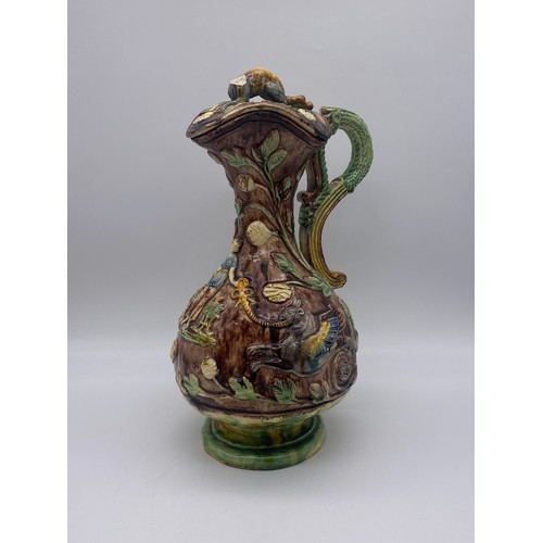 565 - MAJOLICA POTTERY GLAZED EWER AND COVER DECORATED WITH GRYPHONS (FINIAL A/F)