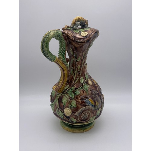 565 - MAJOLICA POTTERY GLAZED EWER AND COVER DECORATED WITH GRYPHONS (FINIAL A/F)