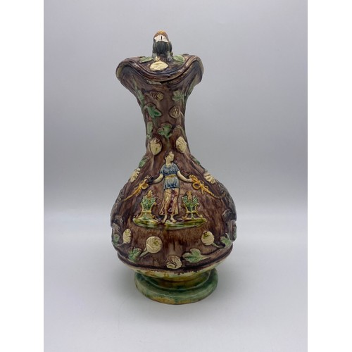 565 - MAJOLICA POTTERY GLAZED EWER AND COVER DECORATED WITH GRYPHONS (FINIAL A/F)