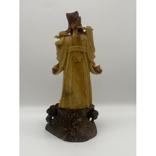 557 - ORIENTAL CARVED RUSSET SOAPSTONE FIGURE OF AN EMPEROR ON A ROCK WORK BASE