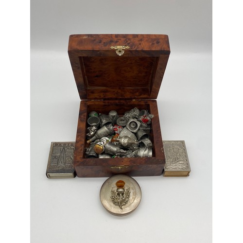 586 - BURR WALNUT EFFECT BOX CONTAINING DECORATIVE PEWTER THIMBLE COLLECTION AND MATCHBOX COVERS
