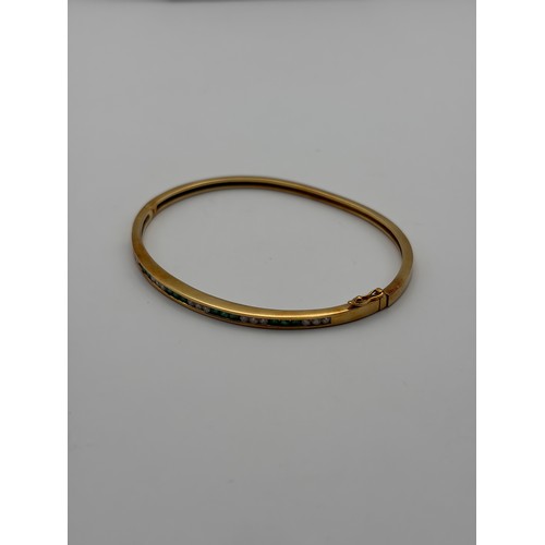411 - 18K 750 DIAMOND AND EMERALD CHANNEL SET BANGLE 12.2G APPROX.