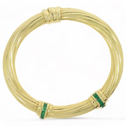 231 - EMERALD SET BANGLE Yellow metal stamped as 18ct but not fully hallmarked. Consists of 2 Emerald set ... 