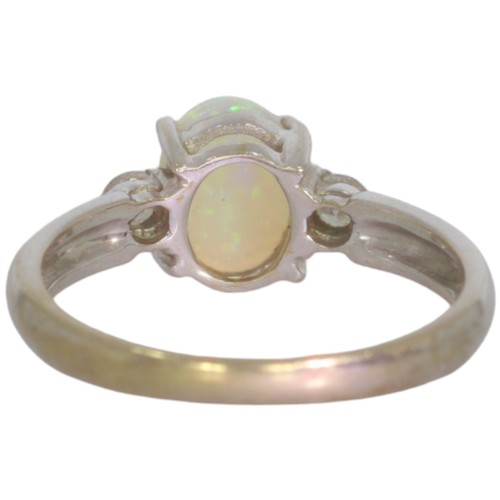 73 - 9ct white gold opal and diamond three stone ring. Set with an oval cabochon opal, and brilliant cut ... 