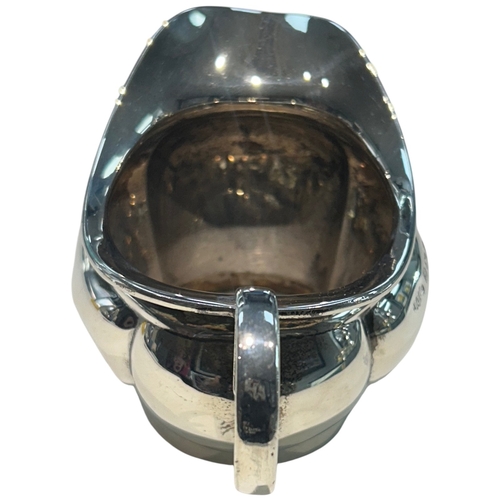 283 - A George V sterling silver cream jug of bulbous circular form, featuring a broad pouring lip and an ... 