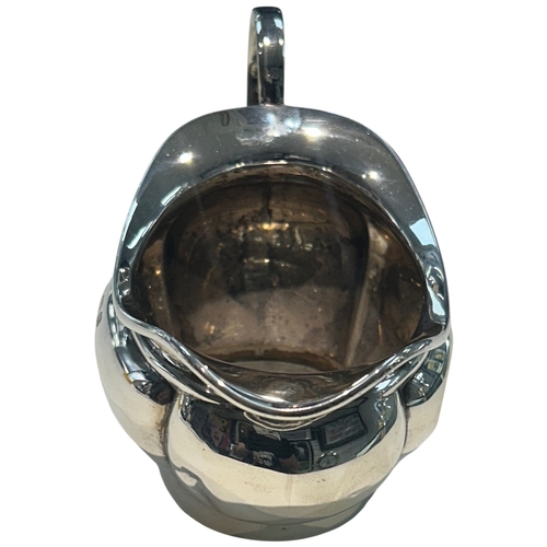 283 - A George V sterling silver cream jug of bulbous circular form, featuring a broad pouring lip and an ... 