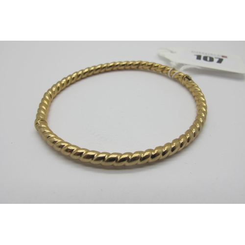 107 - A Modern Bangle, of uniform twisted design, hinged to snap clasp, stamped 