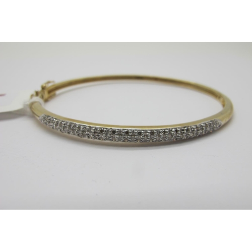 110 - A Modern 9ct Gold Diamond Set Bangle, millegrain set to the front with brilliant cut stones, hinged ... 