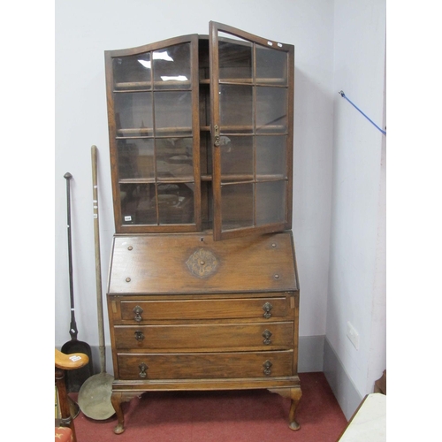 1556 - A 1920's Oak Bureau Bookcase, the top with glazed doors, base with a fall front, fitted interior, th... 