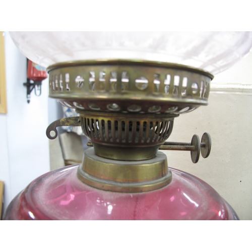 1402 - A Brass Oil Lamp, circa 1900 with eighteen facets to cranberry glass well, etched and tinted shade.