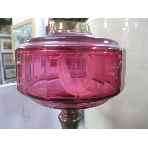 1402 - A Brass Oil Lamp, circa 1900 with eighteen facets to cranberry glass well, etched and tinted shade.