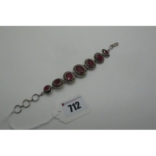 712 - A Modern Ruby Set Bracelet, of graduated oval design, collet set with scroll detail, clasp stamped 