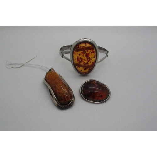 717 - A Modern Amber Set Pendant, og elongated design; together with a modern bangle of amber style and a ... 