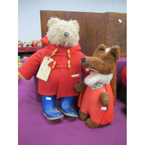 84 - A Paddington Bear Soft Toy, wearing a red duffle coat and blue wellington boots, (lacking hat); toge... 