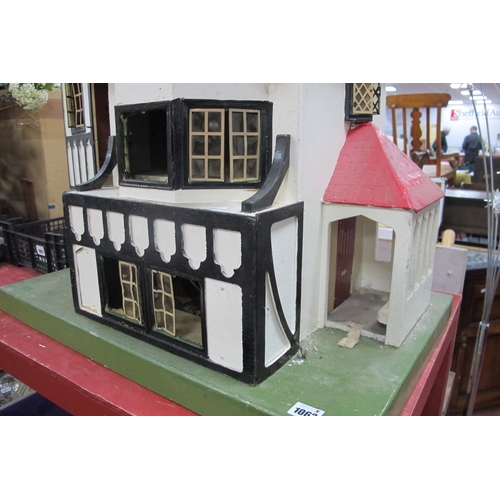 1062 - A Child's Dolls House, with red roof, timber fronted, on a green base.