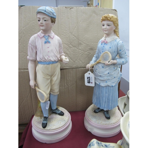 1219 - A Pair of Late XIX Century Continental Bisque Figures, a young boy holding a tennis racquet and ball... 