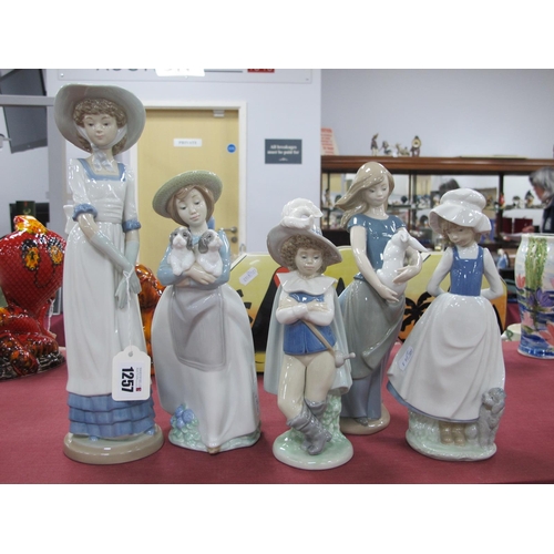 1257 - Nao Figurines, Lady holding a rabbit, 26cm high, girl holding puppies, one larger, two smaller. (5).