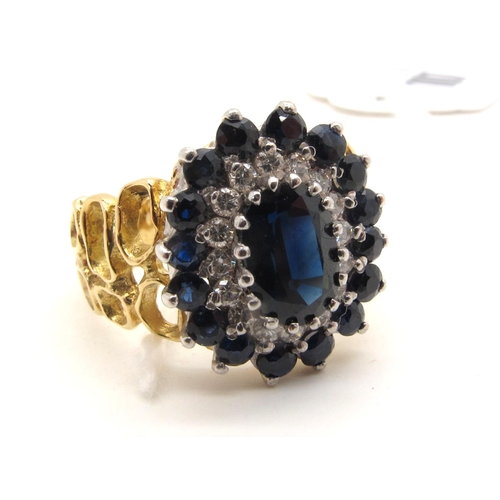 107 - A Large Sapphire and Diamond Cluster Dress Ring, oval claw set to the centre, within two row border ... 