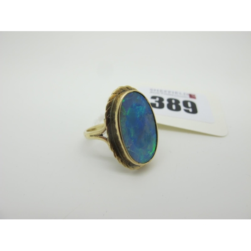 389 - A Large Black Opal Doublet Oval Panel Ring, collet set between bifurcated shoulders (finger size N).