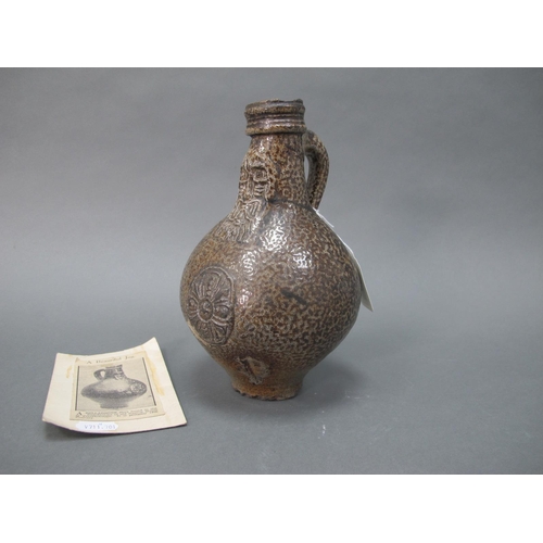 1038 - A German Salt Glazed Bellarmine Jug, moulded with stylised floral roundel and mask face to the neck,... 