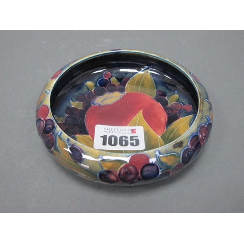 1065 - A Moorcroft Pottery Shallow Circular Dish, painted in the 'Pomegranate' pattern against a sage green... 