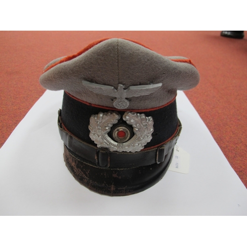 566 - A WWII German N.C.O Peaked Cap, with red artillery piping, metal wreath, cockade and Nazi Eagle incl... 