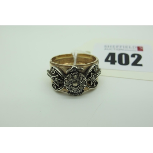 402 - An Antique Style Wide Band, with inset flower head and scroll relief indistinctly stamped 