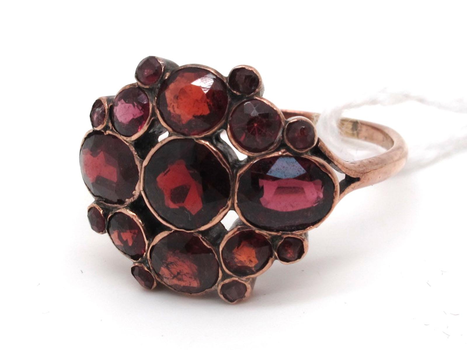 A Garnet Cluster Ring, graduated collet rubover set, between bifurcated ...
