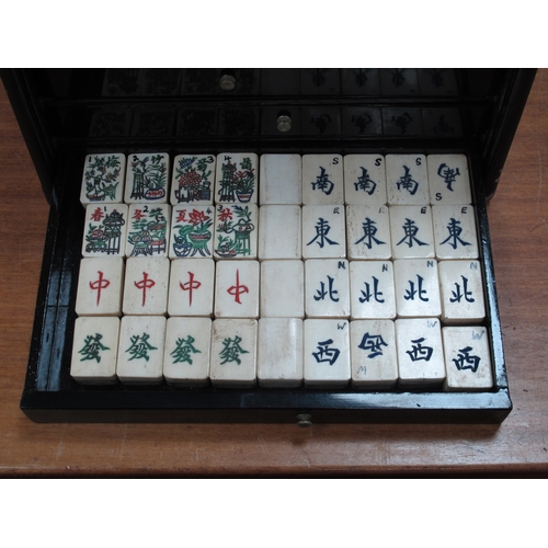 1167 - An Early XX Century Chinese Mah Jong Set, in a lacquered black cabinet with gilt decoration, the lif... 