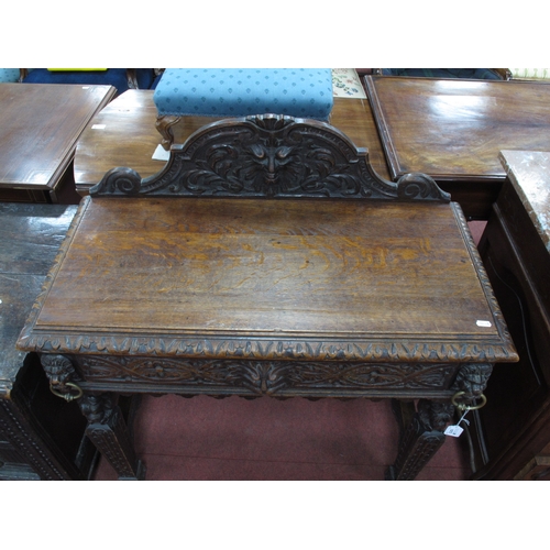 1573 - A XIX Century Carved Oak Side Table, with shaped back carved with a head, single drawer flanked by c... 